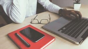 Modern workspace with laptop, smartphone, glasses, and stationery for productivity and digital marketing SEO strategies.
