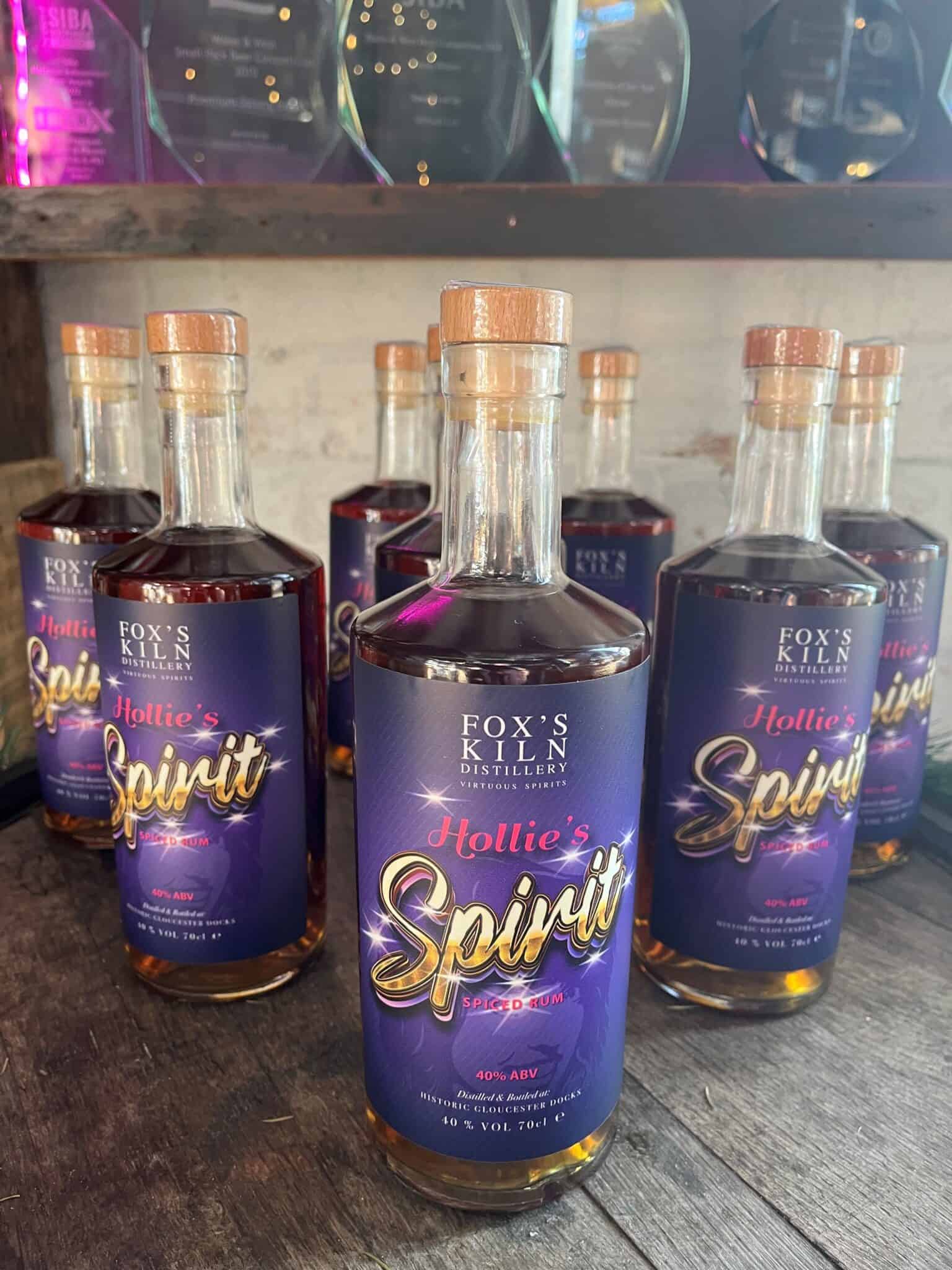 1. Bottles of Hollie's Spirit spiced rum from Fox's Kiln Distillery, with vibrant label design, displayed on a rustic wooden surface.